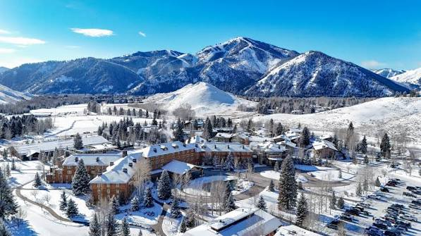 Aerial view of a snow-covered mountain lodge and village below a ski hill